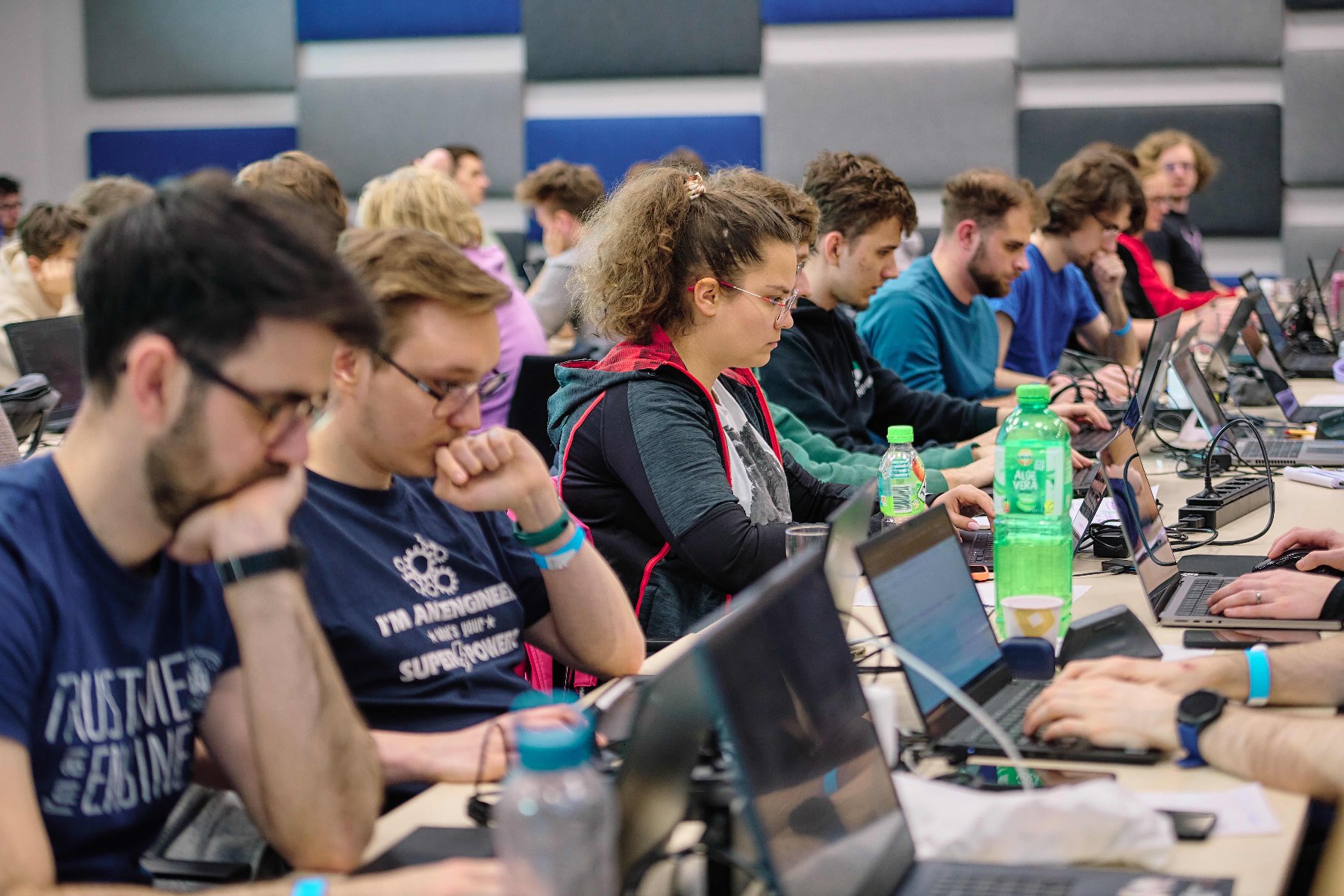 Hackathon took place as part of the Tech of Tomorrow conference in Poznań. A group of people sit at their computers. They are programming thoughtfully.