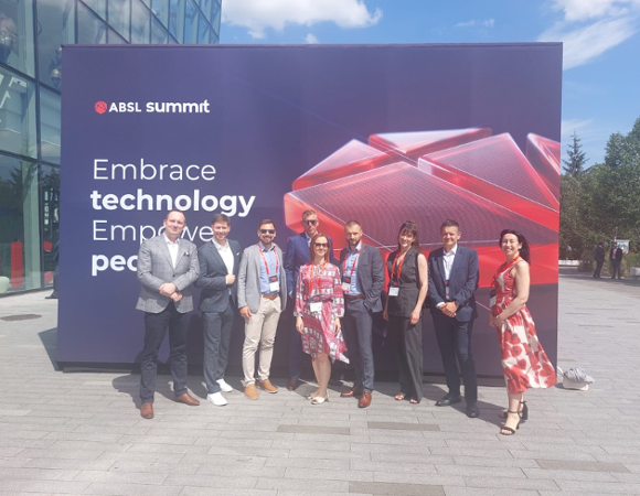 Przedstawiciele Miasta Poznań podczas gali ABSL Poland Summit osoby stojące na tle plakatu ABSL. ubrane oficjalnie, uśmiechają się