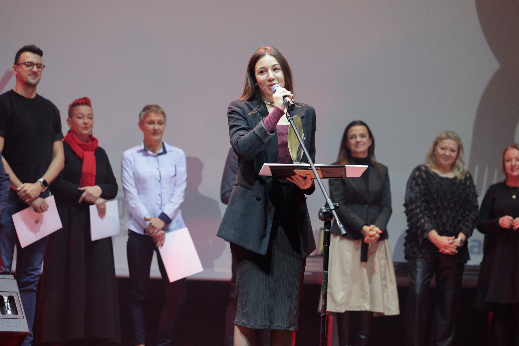 Na zdjęciu znajduje się kobieta - laureatka konkursu w kategorii indywidualnej - która stoi na scenie i przemawia do mikrofonu