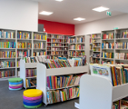 Zdjęcie przedstawia wnętrze biblioteki. Widać na nim półki z książkami.