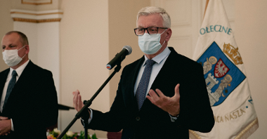 Jacek Jaśkowiak, prezydent Poznania, stoi przy mikrofonie, gestykuluje
