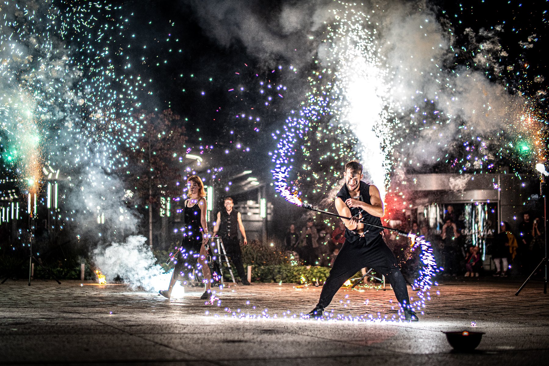 Finał "Łazarskiego Lata" pokaz cyrkowo-ogniowy w wykonaniu AbstractShow Artyści wykonują pokaz fireshow nocą - kobieta i mężczyzna przeprowadzają pokaz z wykorzystaniem ognia, a wokół unoszą się iskry i fajerwerki, podczas gdy publiczność ogląda występ