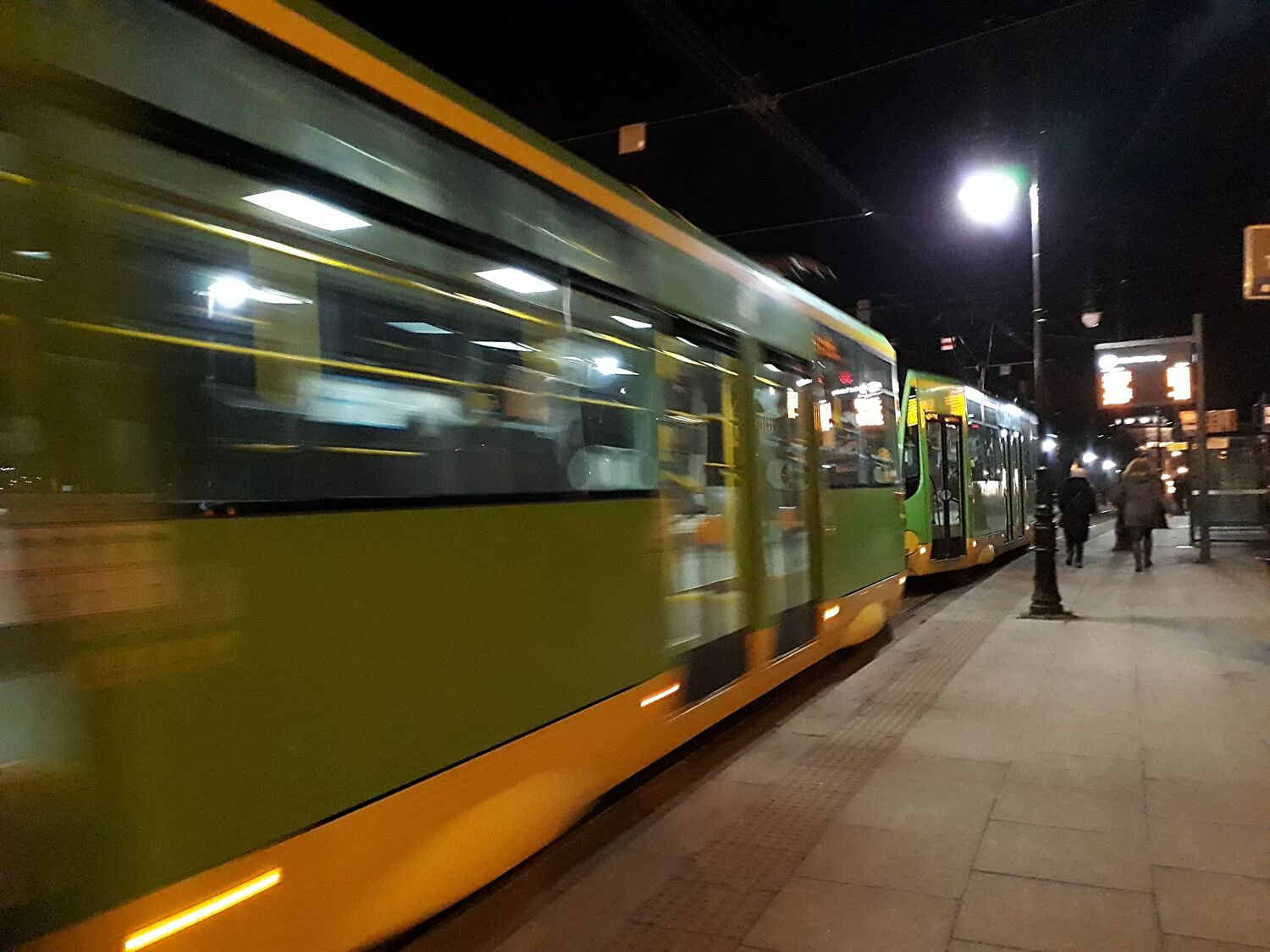 Prace nocne Widko z boku na jadący tramwaj w nocy Tramwaj koloru zielonego..