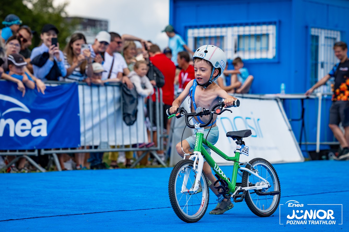 Enea Junior Poznań Triathlon Na zdjęciu młody triathlonista, startujący w kategorii Junior 3 i wyprowadzający swój rower ze strefy zmian podczas imprezy Enea Junior Poznań Triathlon