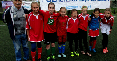 grupa dziewczynek w trojach piłkarskich z trenerem