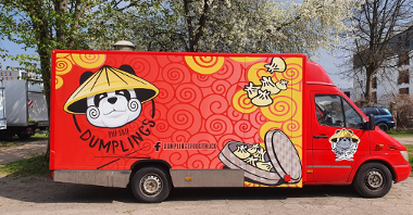 Czerwony food truck stoi bokiem. Na furgonetce grafika z pandą ze słomianym nakryciem głowy. Na grafice są jeszcze azjatyckie pierożki w bambusowym pojemniku.