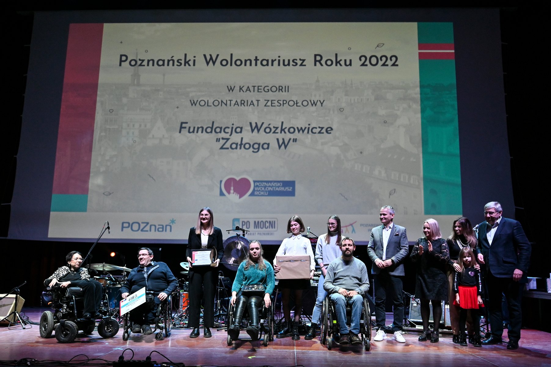 Galeria zdjęć przedstawia osoby stojące na scenie podczas wręczania nagród w ramach konkursu Poznański Wolontariusz Roku 2022. - grafika artykułu