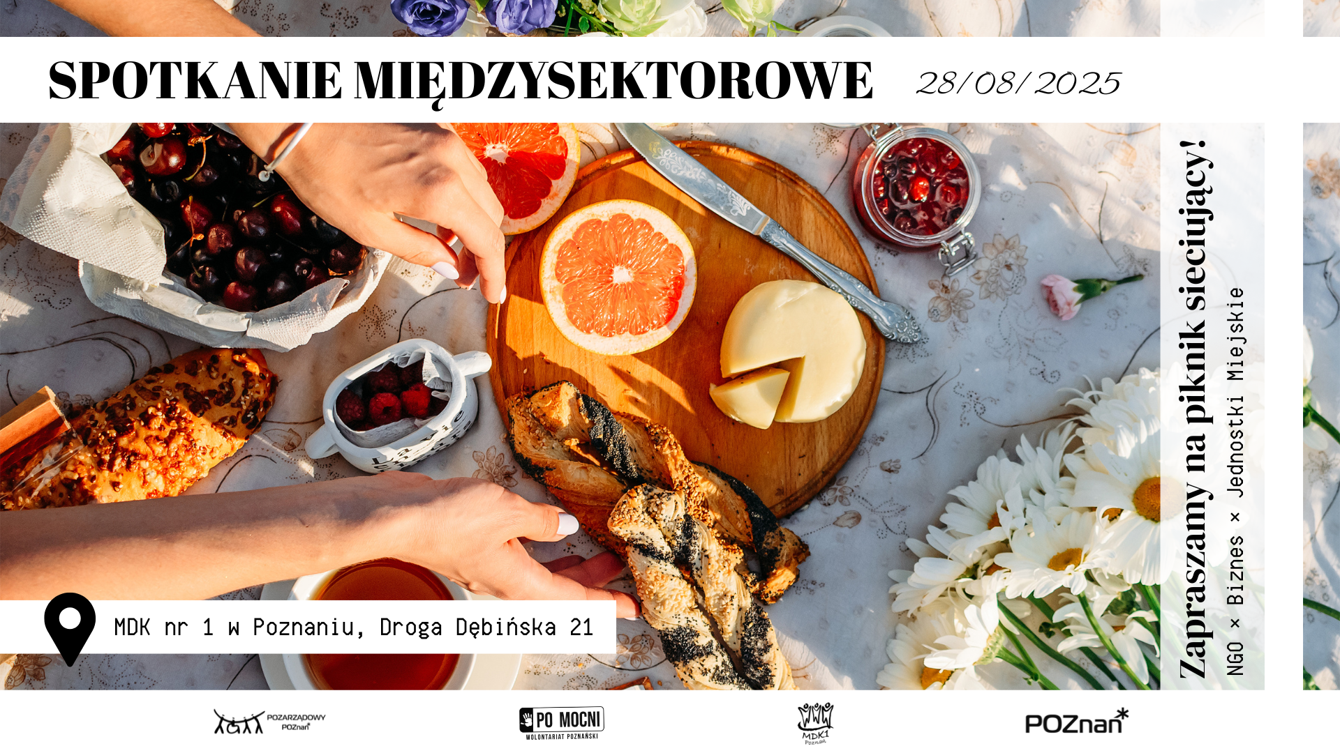 Spotkanie sieciujące w MDK już 28 sierpnia Zdjęcie poczęstunku w formie pikniku, na rozłożonym obrusie owoce, pieczywo, filiżanka herbaty i bukiet kwiatów i sięgajace po jedzenie dłonie