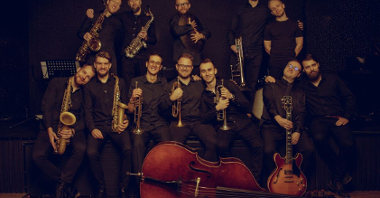 Photo of a band- several men in two rows with their musical instruments. In front of the men, the double bass laying on the floor.