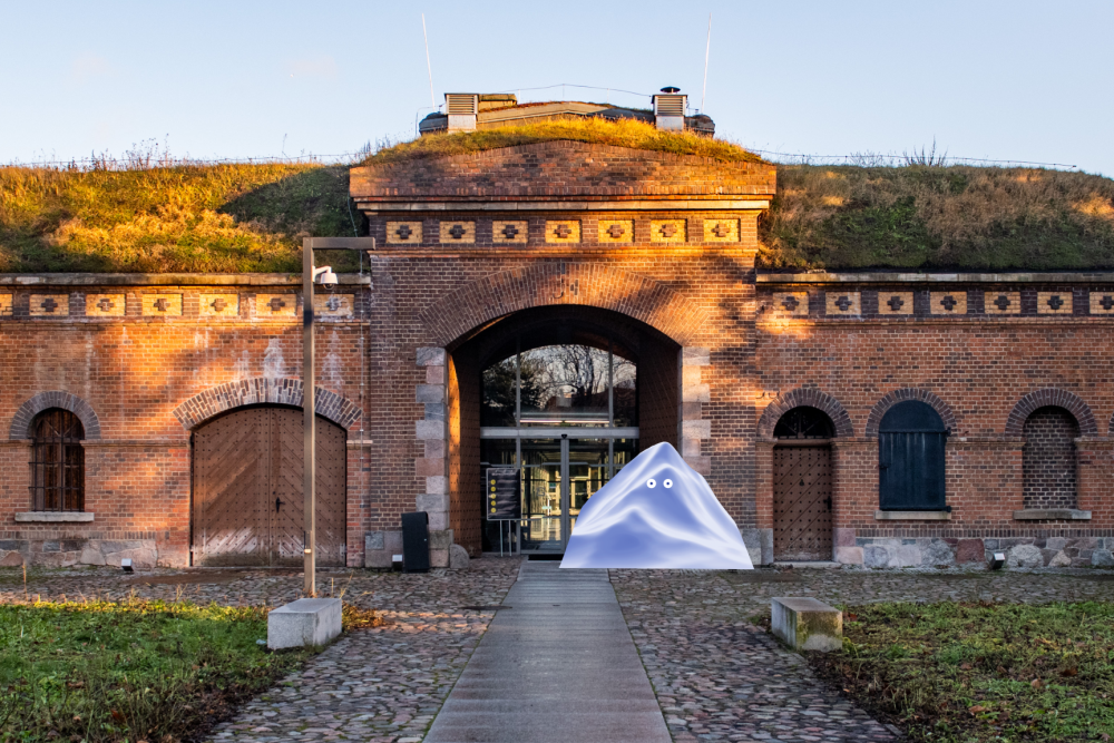 The fort building with a glass entrance gate. In front of the entrance there is a graphic depicting a triangular block of ice with eyes. - grafika artykułu