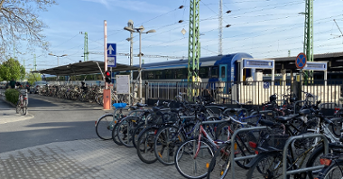 The picture shows a lot of bicycles by the railway station