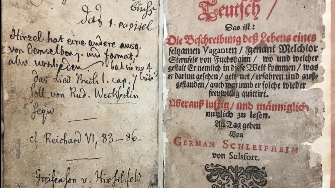 photo of an open old damaged book with visible handwritten notes