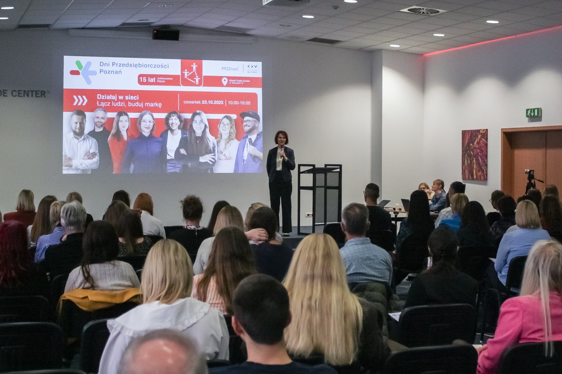 Dyrektor WDGIR-Joanna Jajus, rozpoczynająca 4 dzień Dni Przedsiębiorczości Poznań, prowadzi prezentację przed dużą publicznością w sali konferencyjnej.