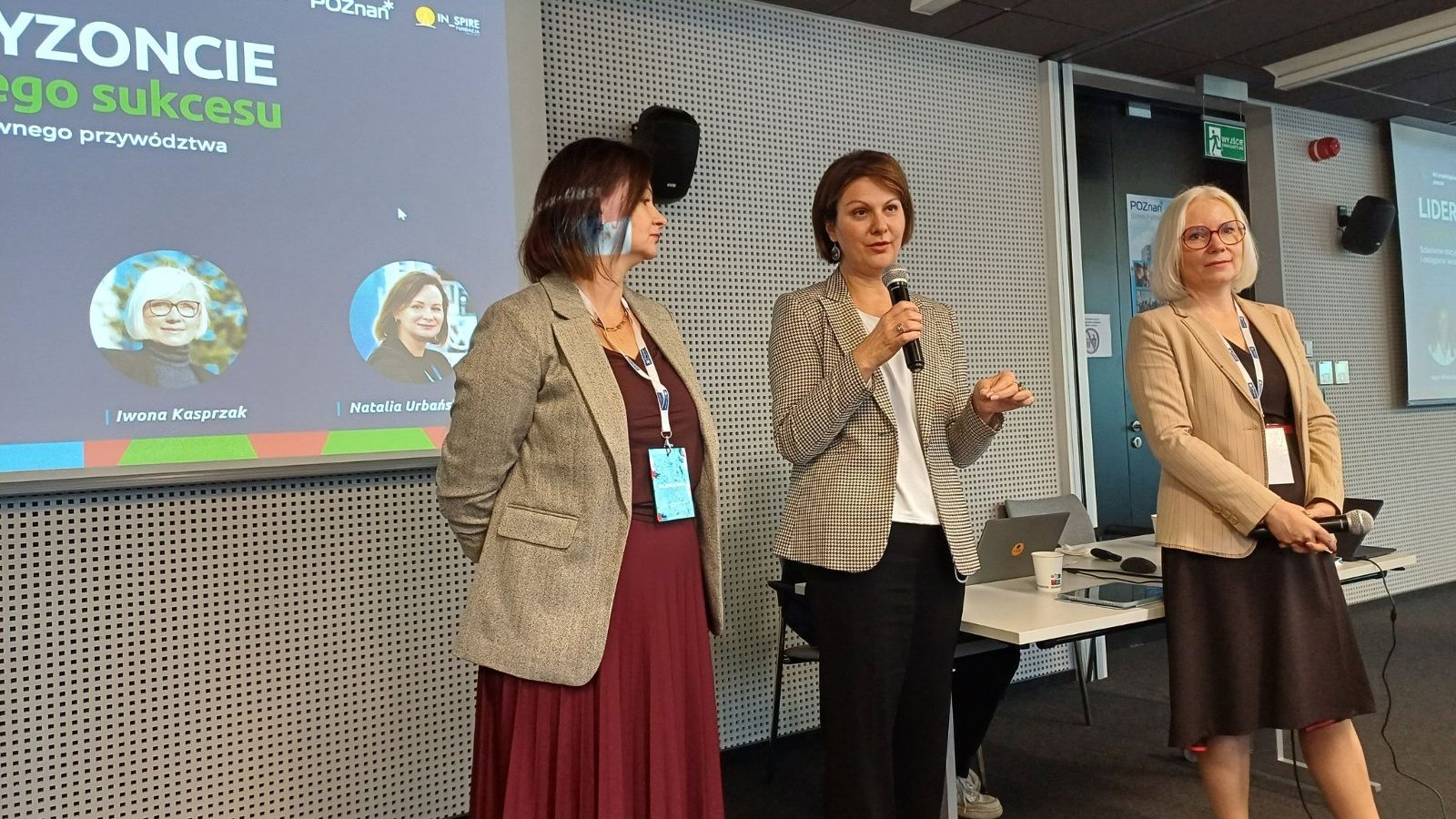 Dyrektor Wydziału Działalności Gospodarczej w obecności dwóch przedstawicielek fundacji In_Spire wita audytorium. W tle wyświetlana grafika promująca konferencję.