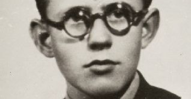 Stara fotografia portretowa młodego mężczyzny w ciemnych włosach i okrągłych okularach ubranego w garnitur.