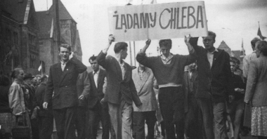 Czarno-biała fotografia strajkujących robotników. Wspólnie trzymają transparent z hasłem "Żądamy chleba".