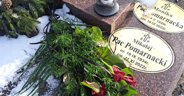 Nagrodeb z tabliczkami. Na nagrobu leżą róże zawinięte czarną wstążką i znicz. Na tabliczkach informacje o narodzinach Mikołaja Paca Pomarnackiego i jego żony Moniki Pac Pomarnackiej.
