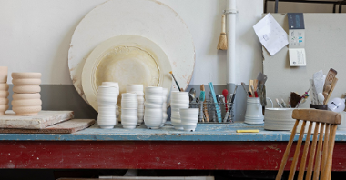 na zdjęciu wnętrze pracowni garncarskiej ukazujące ceramiczne naczynia i narzędzia stojące na stole