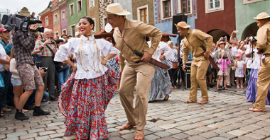 Na zdjęciu para w strojach ludowych tańcząca na Starym Rynku w Poznaniu wśród tłumów.