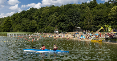 Na zdjęciu widok na plażę, na której znajduje się tłum ludzi kąpiących się i plażujących