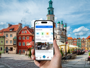 dłoń trzymająca smartfon w tle rynek i ratusz w Poznaniu - grafika artykułu