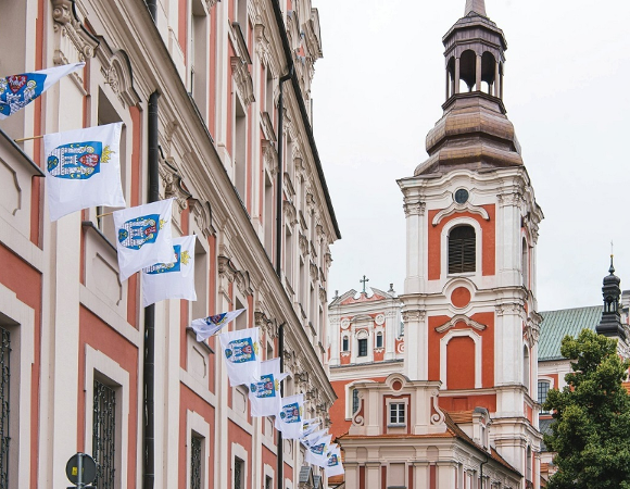 Flagi Miasta Poznania z herbem zawieszone na fasadzie gmachu Urzędu Miasta - więcej w artykule