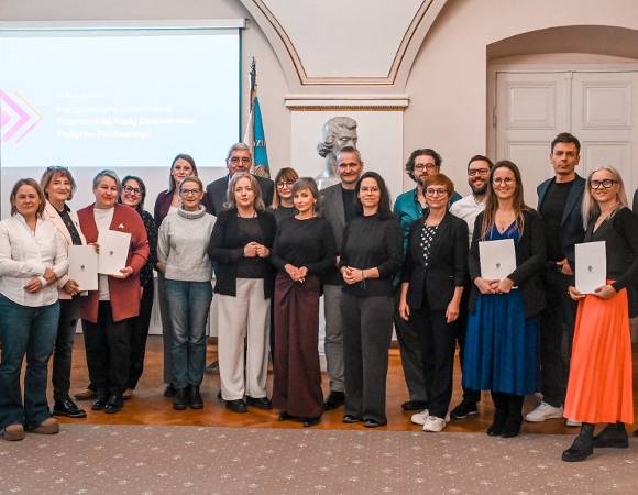 grupa kilkunastu osób kobiet i mężczyzn pozuje do zdjęcia w sali