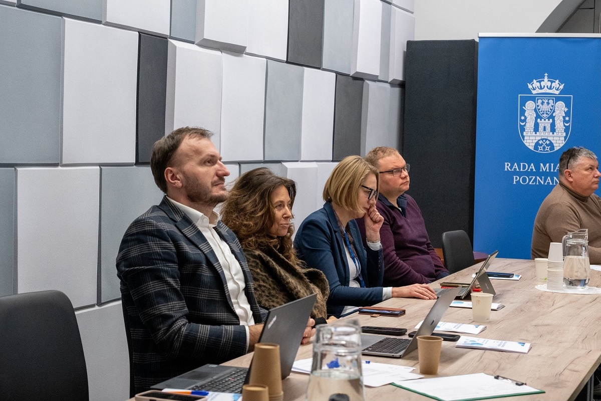 kilkoro osób kobiet i mężczyzn siedzi w sali przy stole konferencyjnym - grafika artykułu