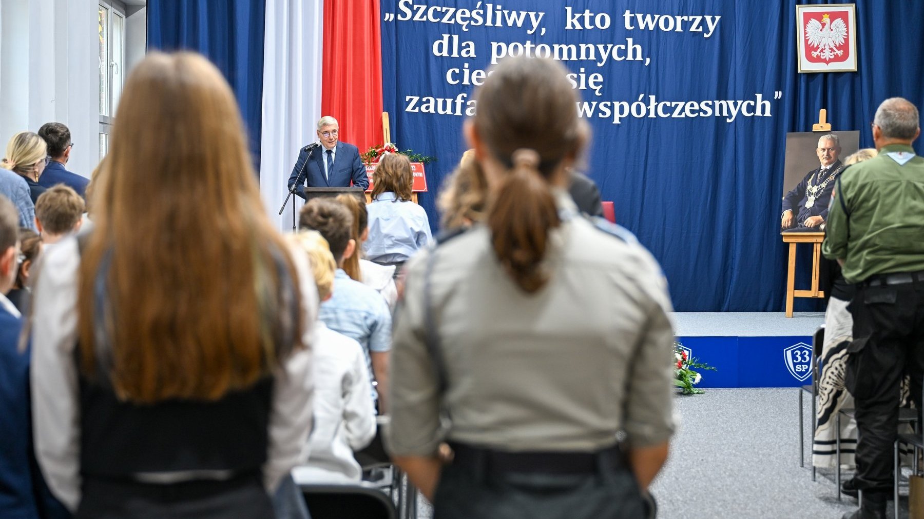 Zdjęcie przedstawia przemawiającego podczas szkolnej akademii przewodniczącego rady miasta.