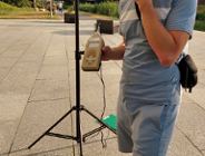 osoba stojąca i trzymająca urządzenie do pomiaru hałasu, nie widać jej twrazy w kadrze - grafika artykułu