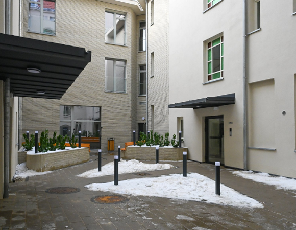 widok od strony wewnętrznego dziedzińca kamienicy, widoczne wejścia do budynku i mała zieleń