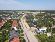 widok z lotu ptaka na zabudowę domów szeregowych i jednorodzinnych wzdłuż drogi, między budynkami rosną drzewa - grafika artykułu