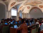 Zdjęcie przedstawia przebieg rady miasta. Radni siedzą przy lożach.