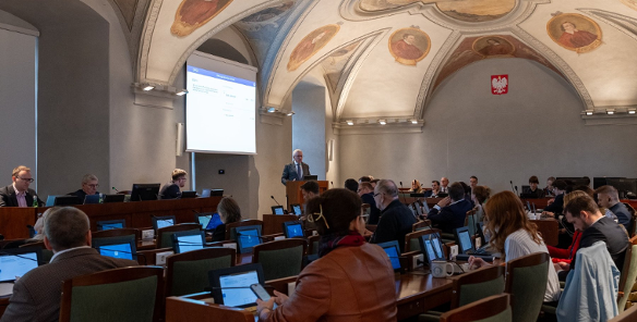 Zdjęcie przedstawia przebieg rady miasta. Radni siedzą przy lożach.