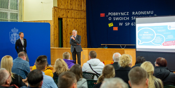 Zdjęcie przedstawia spotkanie mieszkańców w sali sportowej.