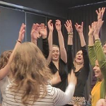 ćwicząca grupa ludzi z podniesionymi rękoma