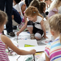 dzieci malują farbami na dużych kartkach