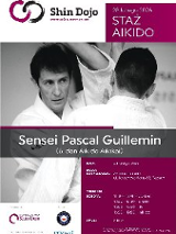 Czarno-białe zdjęcie mężczyzny podpisanego jako "Sensei Pascal Guillemin (6. dan Aikido Aikikai)", rozmawiającego z inną osobą podczas treningu.