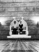 Kobieta i mężczyzna siedzący na podwójnym tronie.