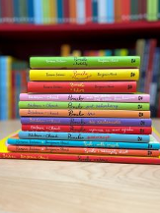 Stos kolorowych książek ułożonych na blacie.
