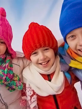 Baner wydarzenia:3 dzieci w kolorowych kurtkach, czapkach i szalikach.