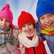 Baner wydarzenia:3 dzieci w kolorowych kurtkach, czapkach i szalikach.