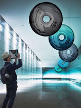 Stojący w pomieszczeniu człowiek przygląda się podwieszonym do sufitu kręgom różnego koloru.