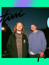 Zdjęcie mężczyzn na tle nocnego nieba w mieście. Widać przewody trakcji tramwajowej i światła samochodów.