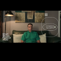 Kadr obrazu na którym widzimy mężczyznę w zielonej koszuli z krótkim rękawem, siedzącego na zielonej dwuosobowej kanapie z dwoma białymi poduszkami za plecami. W tle również lampa stojąca, zaświecona oraz fragment obrazu nad kanapą. Na kadr nałożono logo festiwalu oraz cyklu comedy shorts.