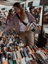 Kobieta przebierająca w książkach wystawionych na bazarze.