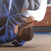 Dwóch zawodników ubranych w białą i niebieską judogę ćwiczy judo.