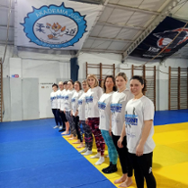 Kobiety w jednakowych koszulkach stoją w rzędzie na macie do ćwiczeń