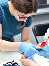 Osoba w rękawiczkach przeprowadza badanie krwi.