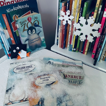 Zdjęcie przedstawia książki i ozdoby świąteczne ułożone na stoliku.